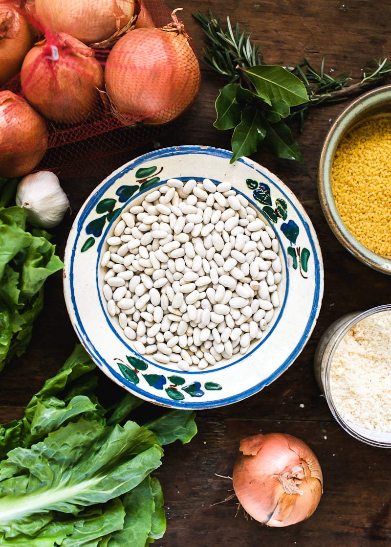 Italian wedding soup ingredients: white beans, escarole, onions, garlic, fresh bay leaves, rosemary, Parmesan cheese, tiny pasta