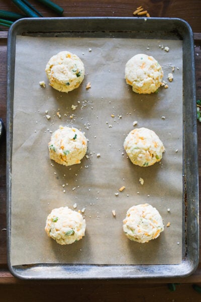 Portioned sourdough biscuit dough on a parchment-lined sheet pan