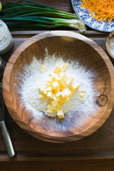 Flour, baking powder, salt & cold cubed butter in a wooden bowl