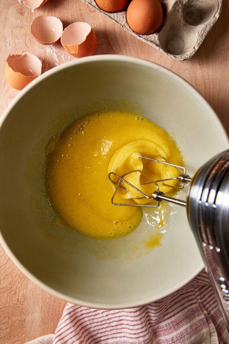 Frothy, beaten eggs and sugar in a large mixing bowl with a hand-held mixer.