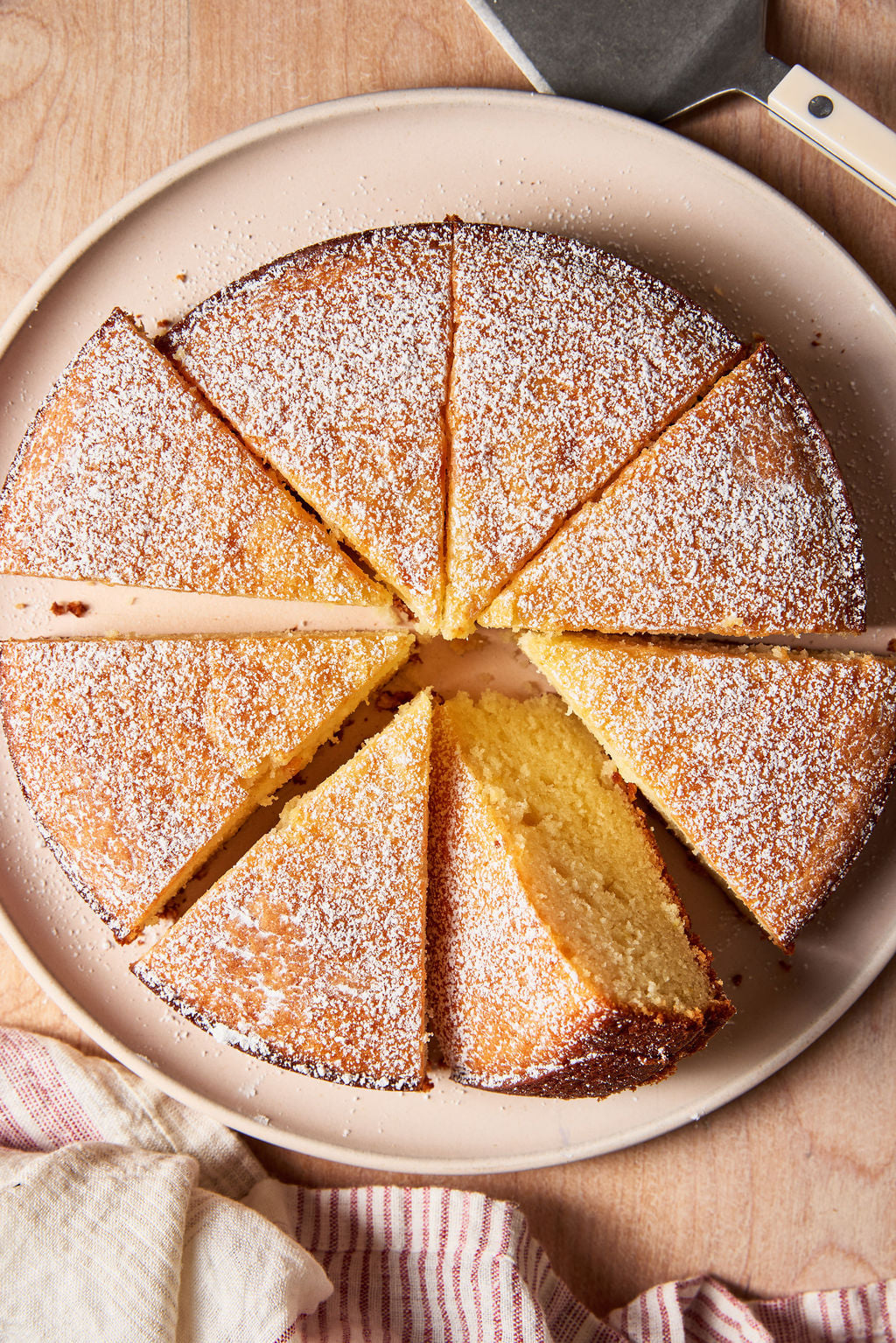 Sourdough French yogurt cake on a pale pink plate with a red and white striped linen towel.