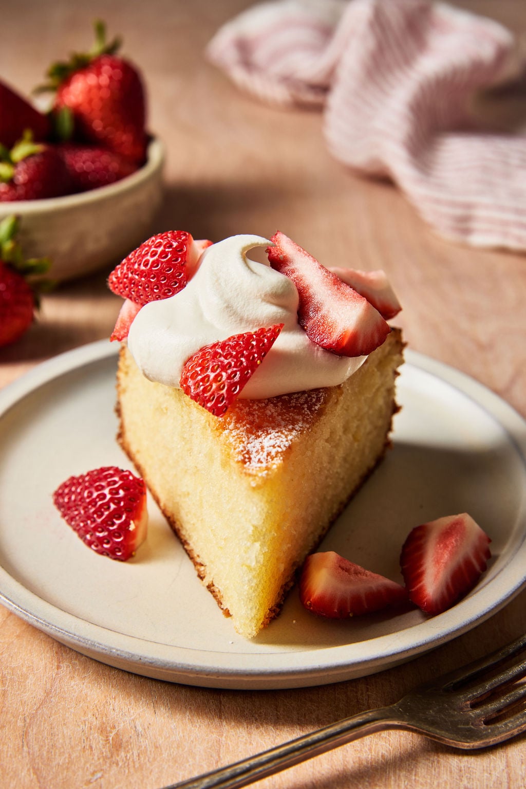 Sourdough French yogurt cake (slice) with fresh strawberries and whipped cream on a pale green plate.