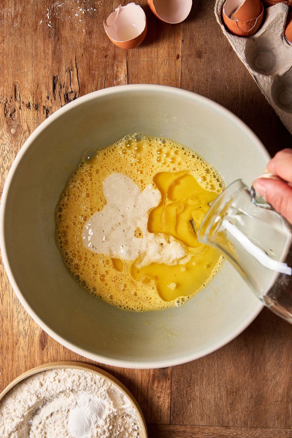 Olive oil added to mixing bowl with whisked eggs and sourdough starter