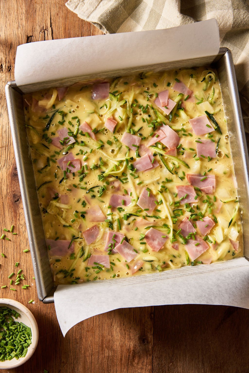 Sourdough zucchini slice batter in a square 8x8-inch pan in preparation for baking