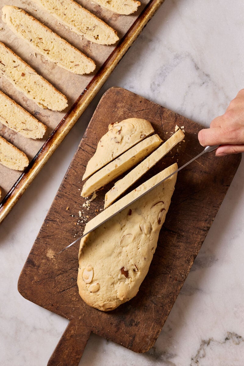 Cutting baked sourdough biscotti into thin slices.