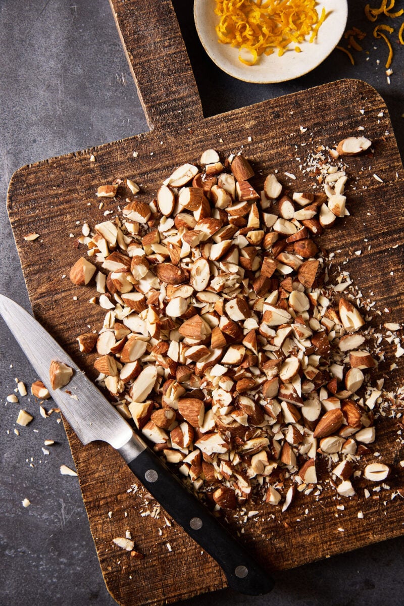 Toasted, chopped almonds on a wooden cutting board.