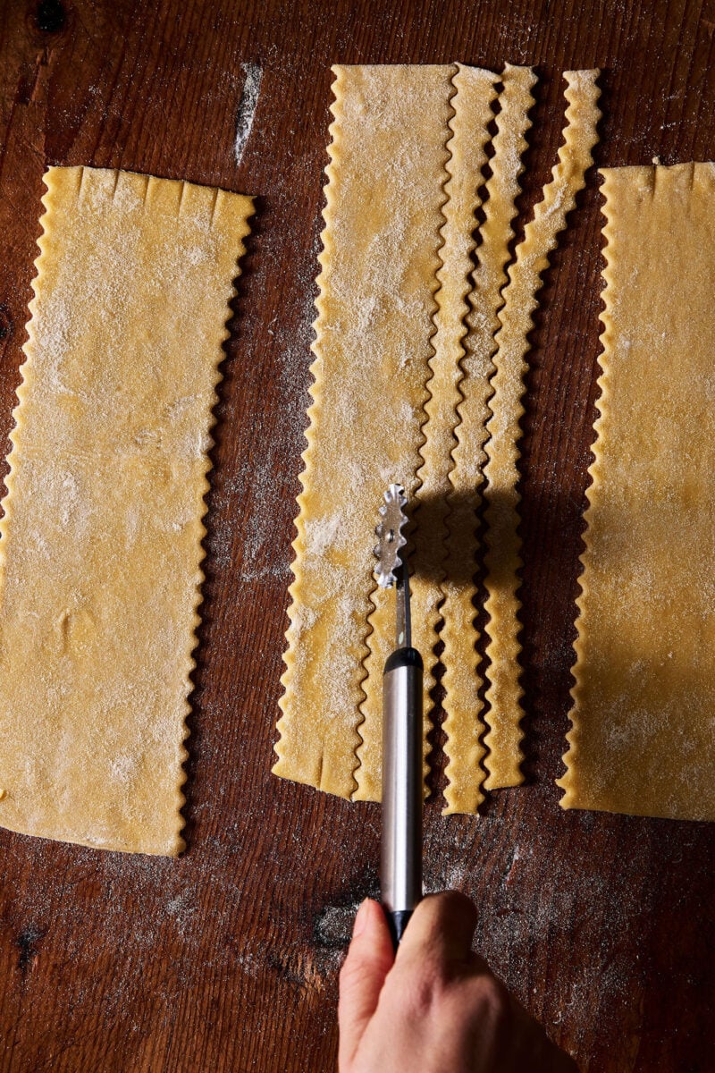 Cutting sourdough mafaldine pasta by hand with a fluted pastry wheel.