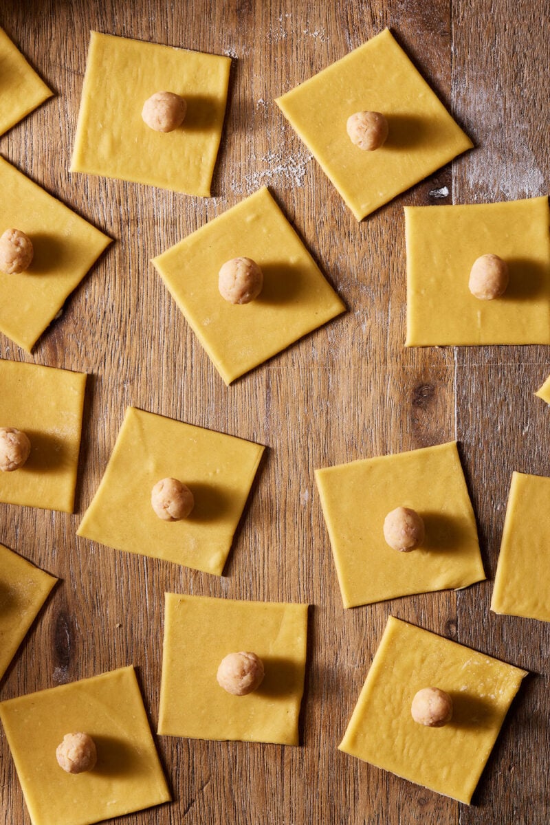 Many pasta squares with pork filling arranged assembly style.