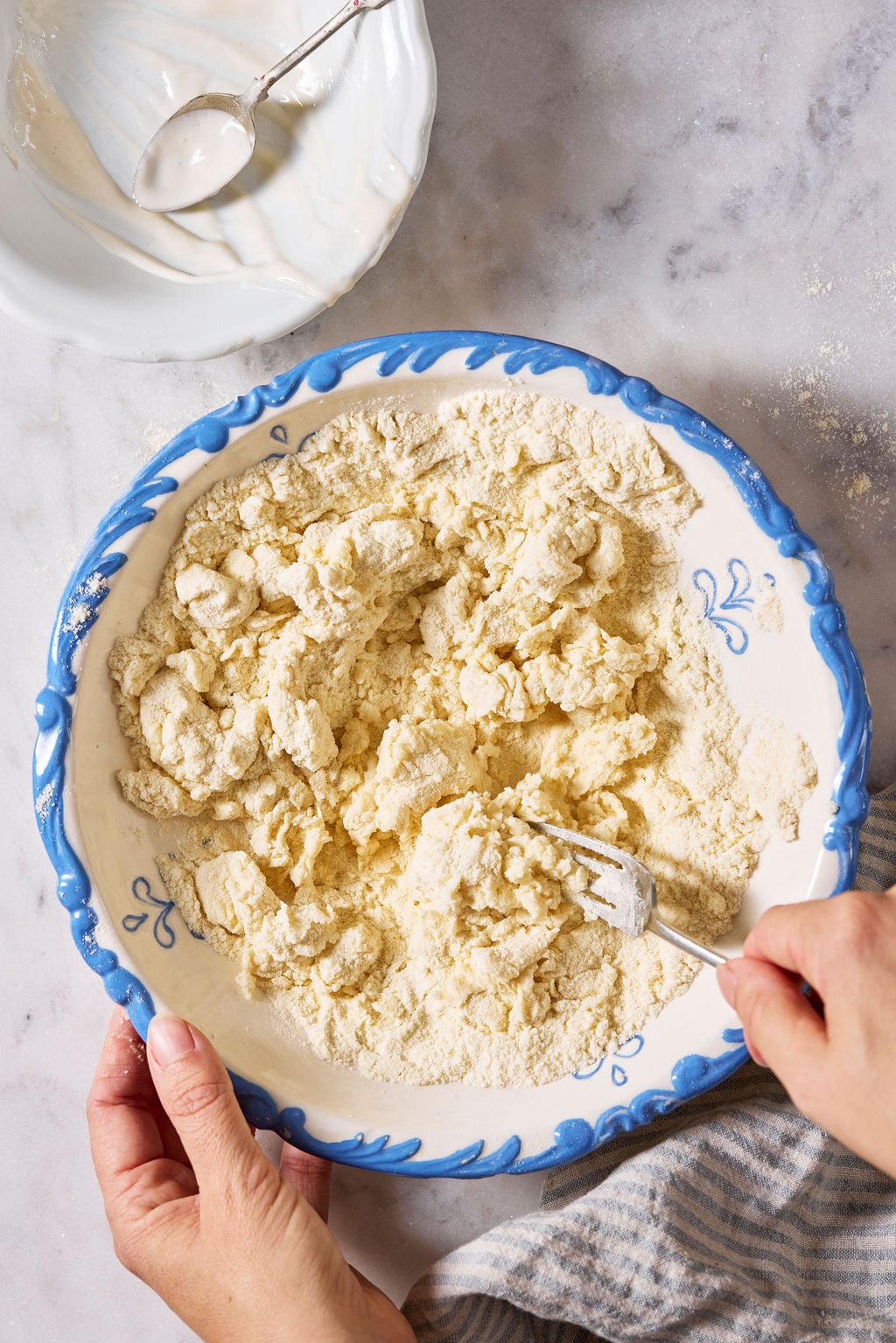 Sourdough semolina pici dough (crumbly texture) in a large white bowl with a blue rim.