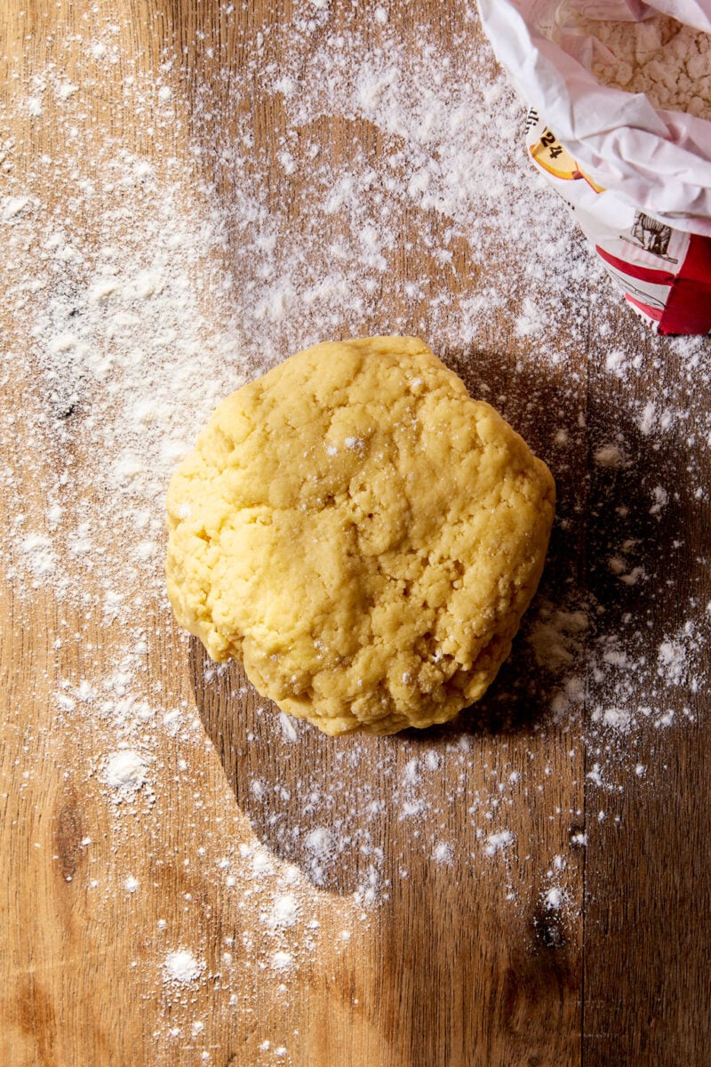 Sourdough tortellini dough formed together by hand on a flour dusted wooden surface.