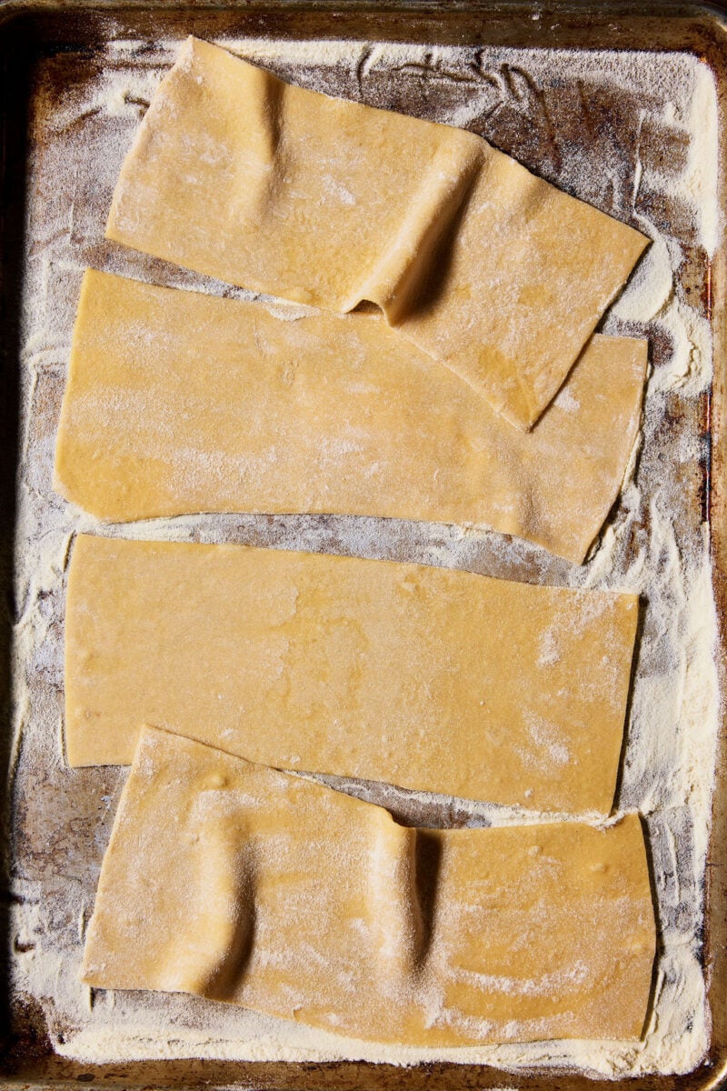 Sourdough mafaldine pasta sheets arranged on a semolina-dusted sheet pan