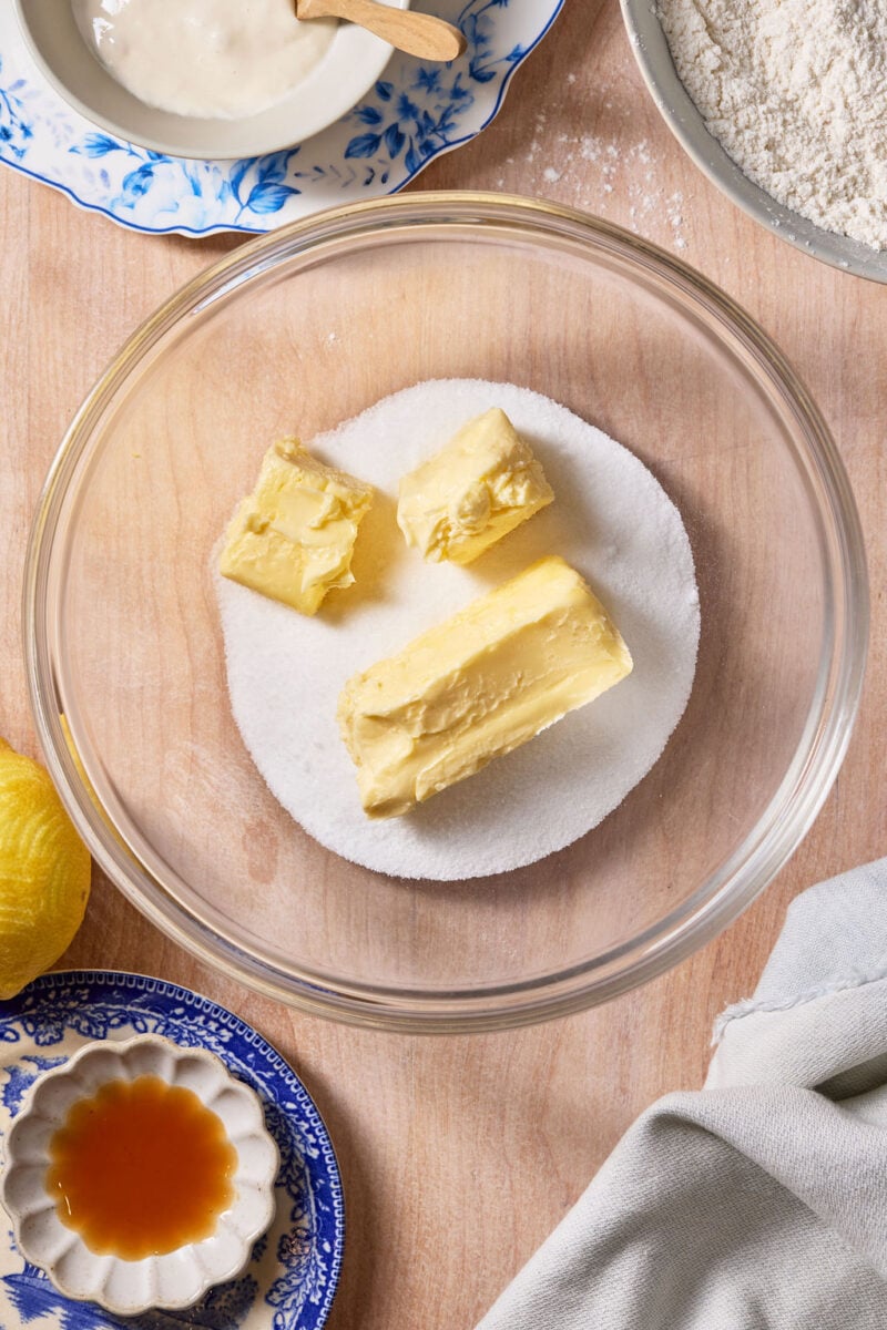 Sticks of butter and granulated sugar in a large glass mixing bowl