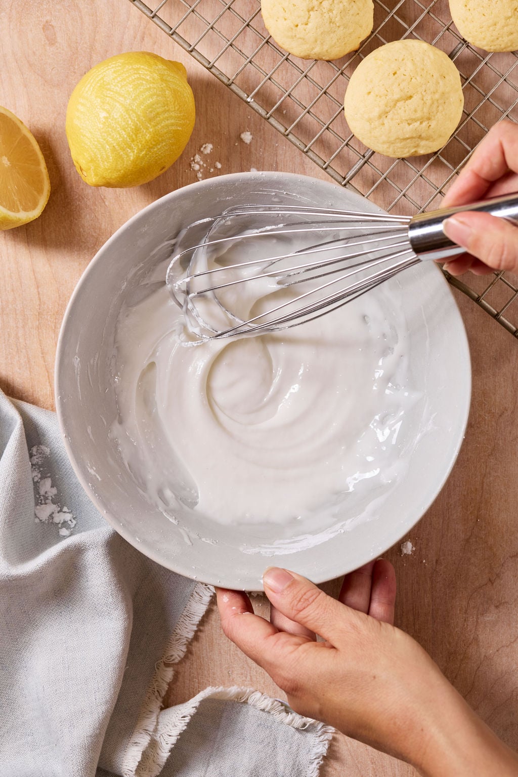 Smooth, whisked lemon glaze in a white bowl: sifted powdered sugar, lemon juice and milk.