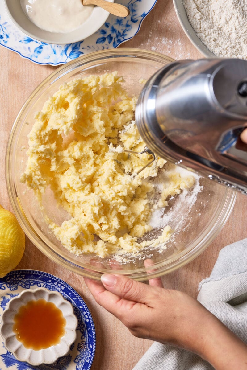 Creamed butter and sugar in a glass mixing bowl with a handheld mixer