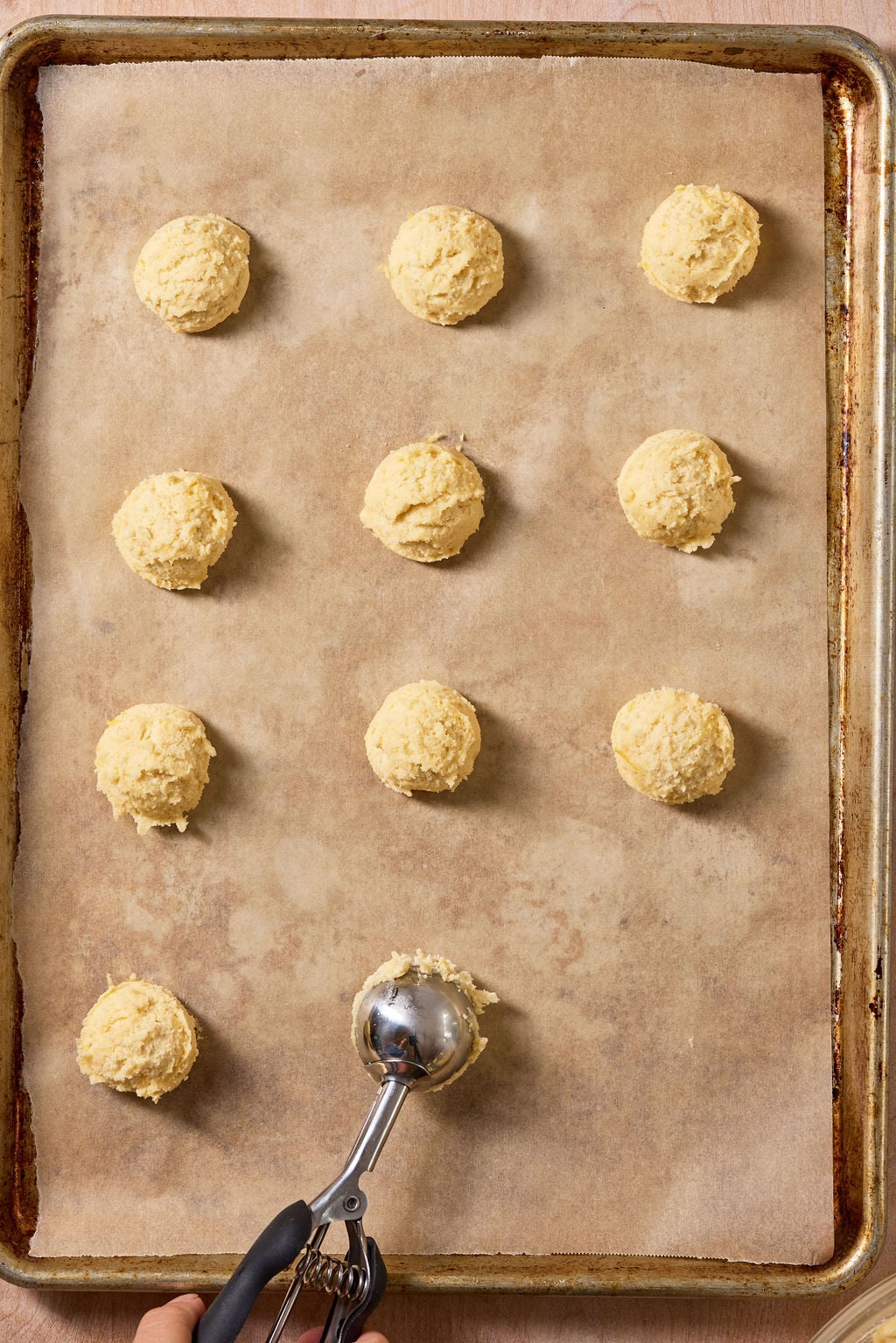 Sourdough lemon drop cookies portioned using a cookie scoop onto a parchment-lined sheet pan