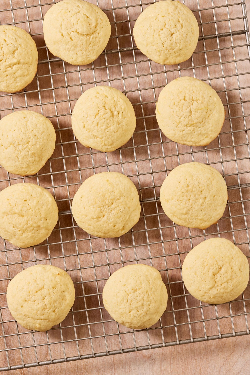 Baked sourdough lemon drop cookies on a wire metal rack set over a parchment-lined sheet pan