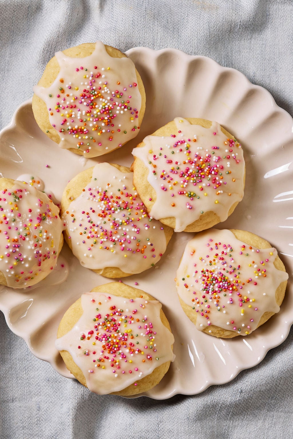 Glazed sourdough lemon drop cookies with colored sprinkles on a blush pink plate