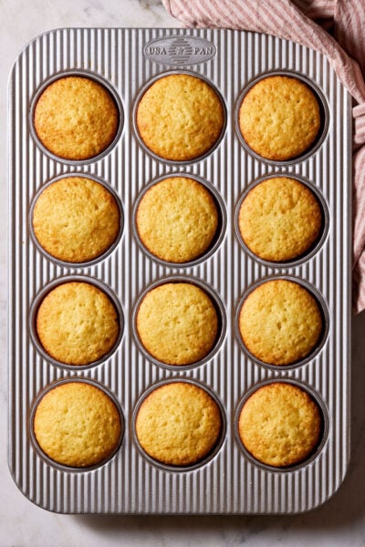 Baked, unfrosted, sourdough French yogurt cupcakes in a muffin tin.