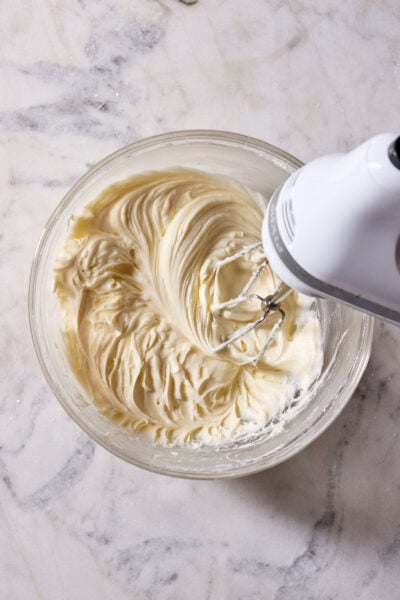 Swirls of cream cheese frosting in a glass mixing bowl.