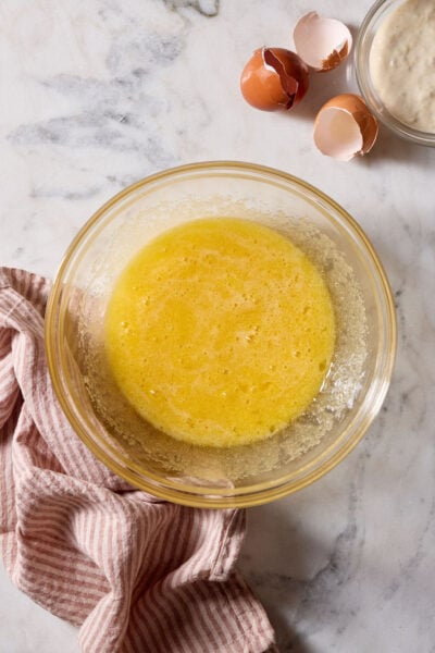 Frothy mixture of eggs and sugar, beaten together in a glass bowl with a hand-held electric mixer.