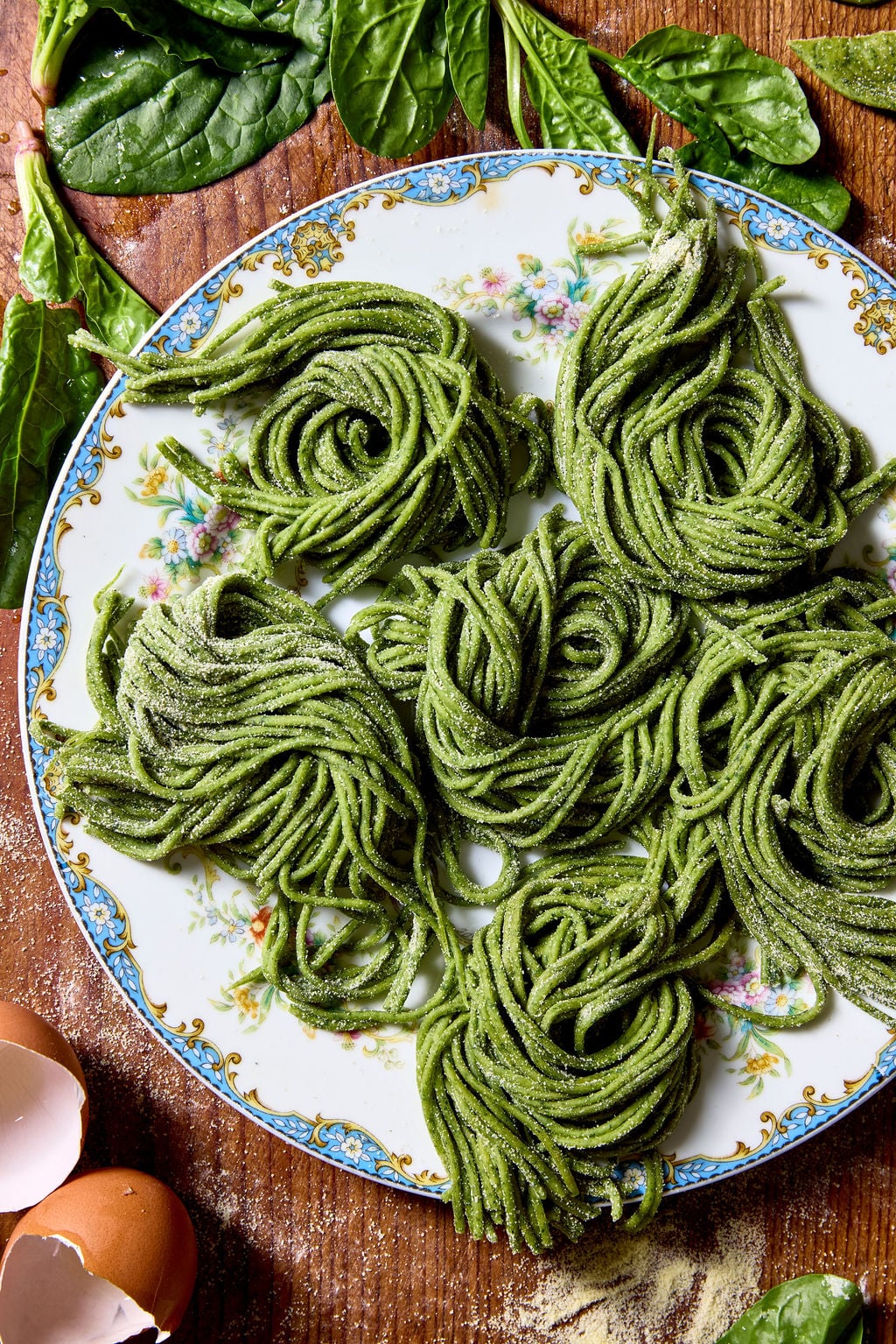 Sourdough spinach pasta arranged in coiled nests on a vintage plate on top of a wooden surface.